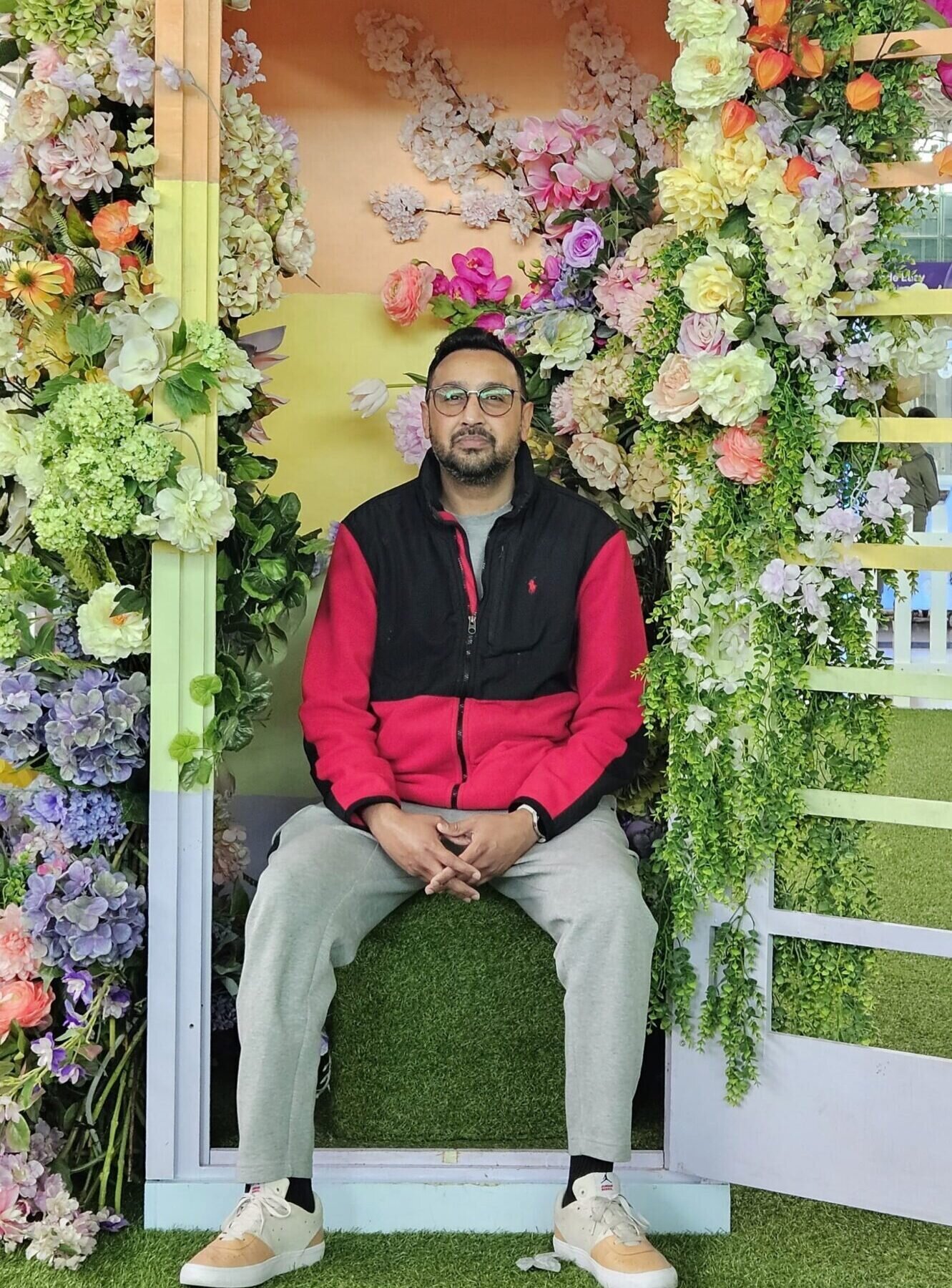 Mohammad poses seated in a telephone box brightly decorated with beautiful flowers.