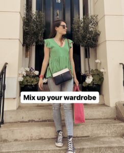 Amy, in a green shirt and sunglasses standing on steps showcasing her fashion creativity with a stoma.