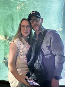 Chris and his wife pose for a photo in an aquarium, enjoying life post-stoma!