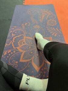 Amy sits on her exercise mat, feet on the floor, enjoying a moment of calm and relaxation.